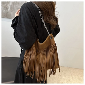 Détail d'un sac seau en daim marron avec de longues franges bohèmes et chaîne en argent