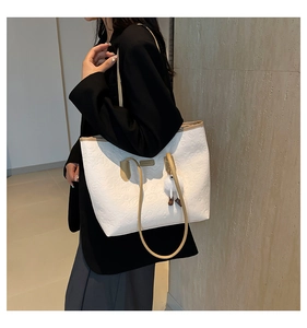 Detail of white tote bag featuring embossed cartoon patterns and soft plush charm