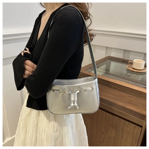Silver metallic shoulder bag detail showing drawstring design and golden metal eyelets