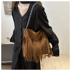 Detailed view of bohemian brown suede bucket bag with long fringe and silver chain strap