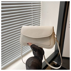Detail of minimalist beige faux leather shoulder bag with gold metal clasp and strap