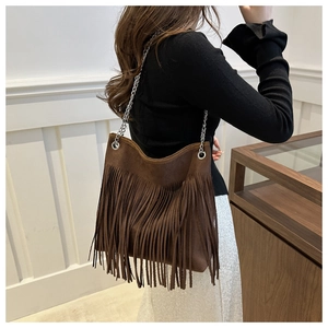 Detail of dark brown suede shoulder bag with long fringes and silver metal chain strap