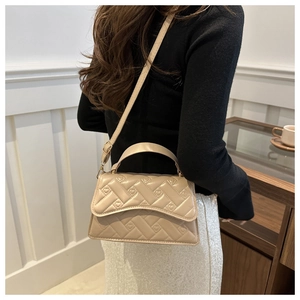 Detail of beige quilted handbag with heart embroidery textures and gold hardware accents