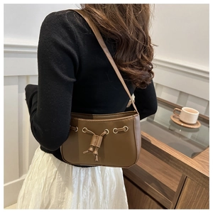 Brown leather underarm bag featuring drawstring detail and gold ring buckle on shoulder