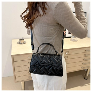 Chic black quilted handbag with geometric stitching shown on a model in a home setting
