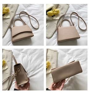Detail view of beige crocodile embossed handbag with woven handle and gold hardware accents