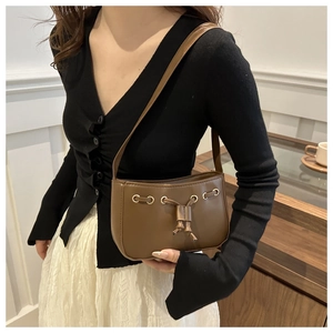 Detail of deep brown drawstring shoulder bag in PU leather worn by a model