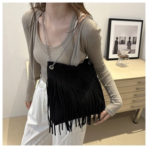 Détail du sac seau noir en daim avec de longues franges et une bandoulière chaîne argent