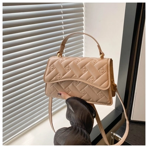 Close-up of beige square crossbody bag with quilted lattice texture and top handle