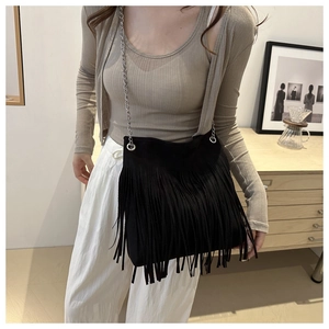 Close-up of black suede bucket bag featuring long fringes and silver chain strap