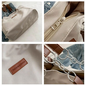 Detail view of large nylon tote bag featuring chain straps and smooth metal zipper closure