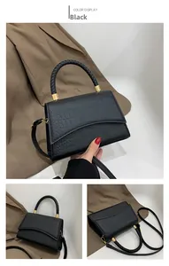 Detail of black crocodile texture handbag with woven handle and gold hardware