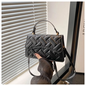 Close-up of black heart-quilted crossbody bag with elegant gold hardware and top handle