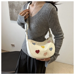 Detail of white crescent bag with colorful heart patches on artificial leather