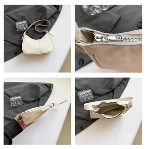 Detail view of white quilted crescent bag showing silver zipper and spacious interior