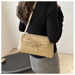 Chic beige bow-style crossbody bag shown on model in a minimalist indoor setting