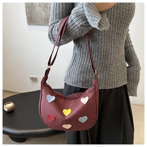 Detail of burgundy crescent bag featuring colorful 3D heart-shaped applique patches