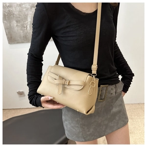 Close-up of beige crossbody bag with textured leather, gold hooks, and buckle detail