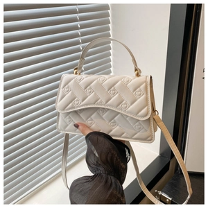Detail of white quilted handbag featuring heart-shaped stitching and gold-tone hardware