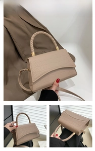 Detail view of khaki faux leather handbag with crocodile pattern and braided handle