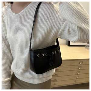 Minimalist black leather underarm bag with gold metal eyelets and decorative drawstring