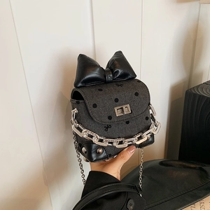 Mini crossbody bag with grey polka dot pattern, large black bow and silver chain strap