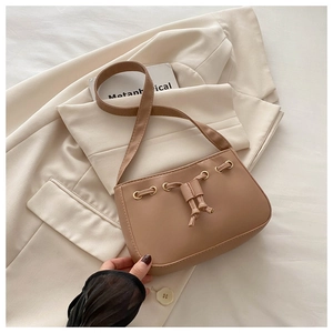 Detail of light brown crescent shoulder bag with drawstring accents and gold eyelets