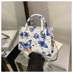 Dettaglio borsa squadrata bianca con stampe di farfalle blu e doppi manici tondi