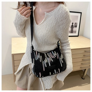 Detail of black crossbody dumpling bag featuring colorful embroidery and wide strap