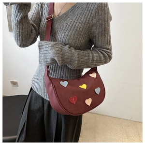 Detail of burgundy half-moon shoulder bag with colorful heart-shaped leather patches
