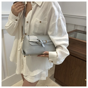 Detailed view of silver bow-knot crossbody bag with shimmering pearlescent coating and gold buckle