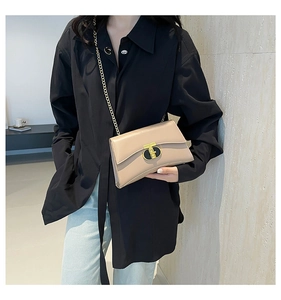 Détail d'un sac bandoulière beige avec fermoir en T doré et bandoulière en chaîne