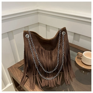 Detail of a brown suede bag featuring long fringe tassels and silver chain straps