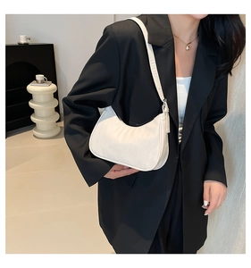 Close-up of minimalist white crescent underarm bag on model in black suit jacket