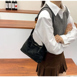 Close-up of black pleated tote bag featuring an amber resin ring on the shoulder strap