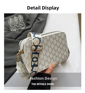 Close-up of cream crossbody bag featuring monogram M pattern and wide fabric strap