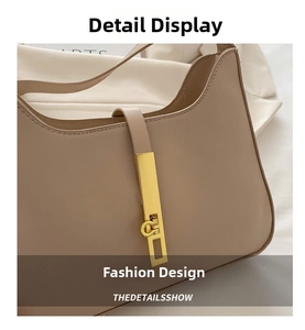 Close-up of beige leather shoulder bag featuring a sleek gold metallic bar buckle closure