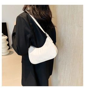 Rear view of a model wearing a white crescent-shaped hobo bag with a black suit jacket