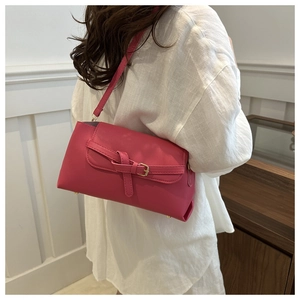 Detailed side view of rose red shoulder bag with gold rivets and leather strap on model