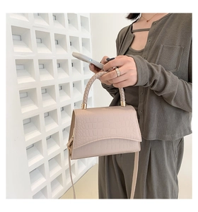 Detail of elegant crocodile-patterned handbag with woven handle and shoulder strap