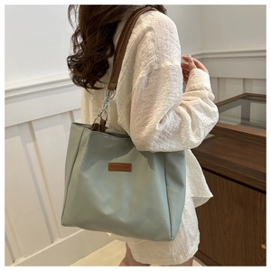 Detail of mint green nylon tote with brown leather straps and silver chain hardware