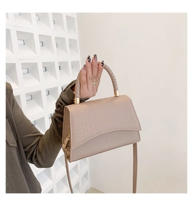 Detail of crocodile embossed crossbody bag with woven handle and gold metal hardware