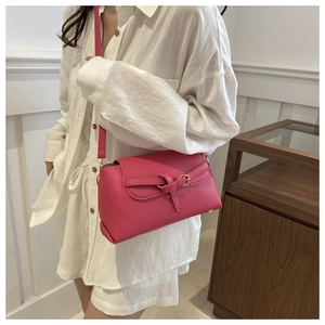 Close-up of rose red textured leather bag with gold buckle and protective bottom studs