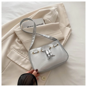Detail of silver crescent shoulder bag featuring drawstring knots and metallic eyelets