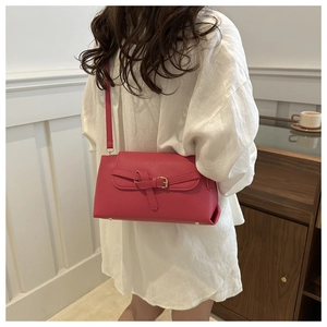 Detail of magenta faux leather crossbody bag with golden buckle on a white background