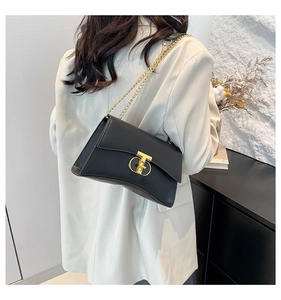 Détail du sac à bandoulière noir avec fermoir en T doré et chaîne portée par le mannequin