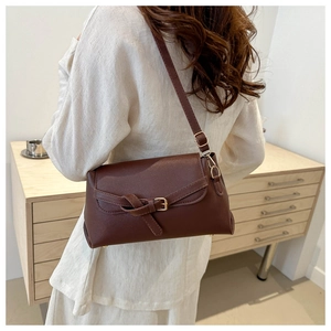 Detail view of brown leather crossbody bag with vintage buckle and gold hardware