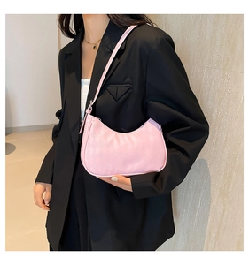 Close-up of pink hobo shoulder bag with textured fabric on a model in a black blazer