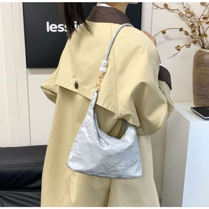 Detail of silver metallic hobo bag with pearl strap on model in beige trench coat