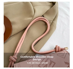 Detail of pink leather handbag showing the knotted strap design and gold metal accents